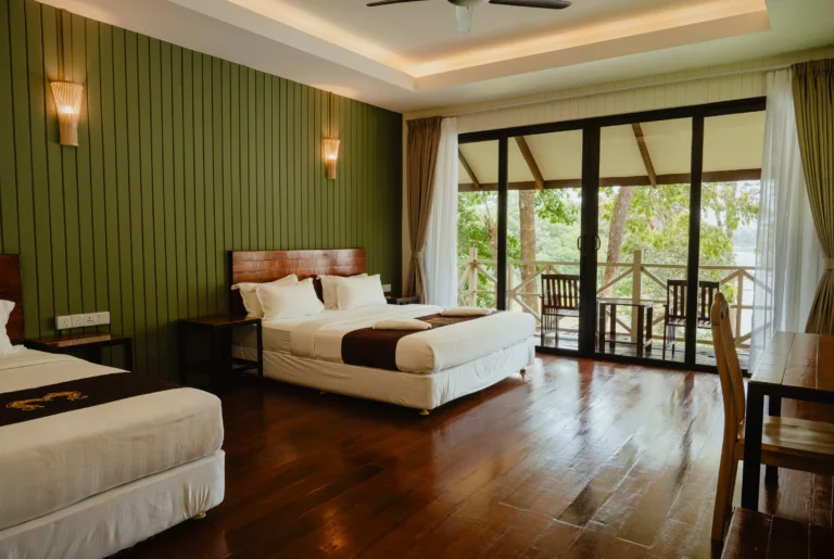 River Chalet interior with king bed and river-facing balcony at Hornbill Lodge, Kinabatangan